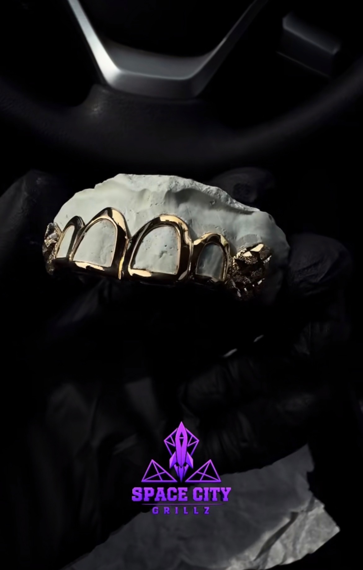Gold open-face grillz with nugget-style end teeth on a white dental cast held with black gloves