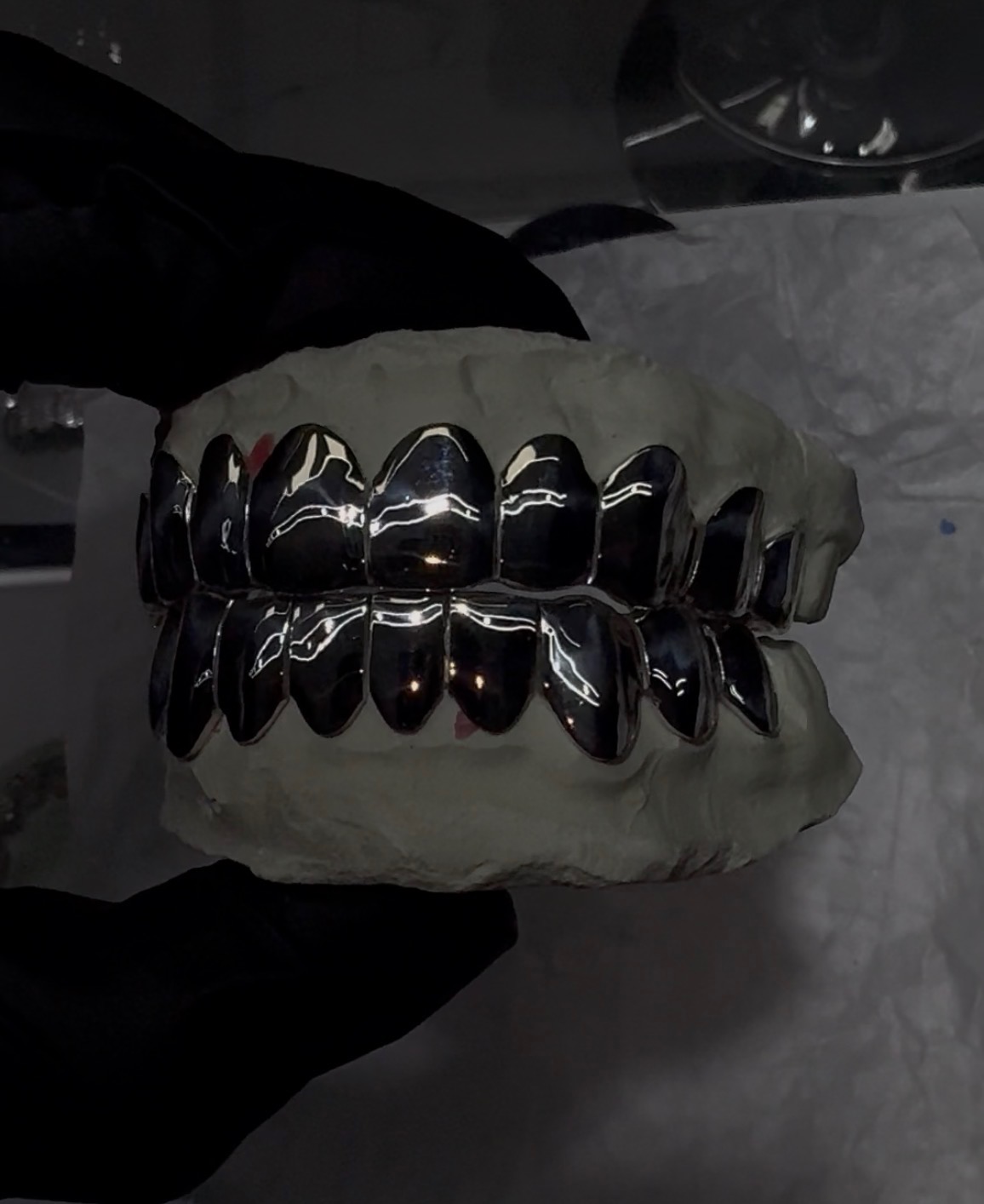 Polished silver full-set grillz on a mold
