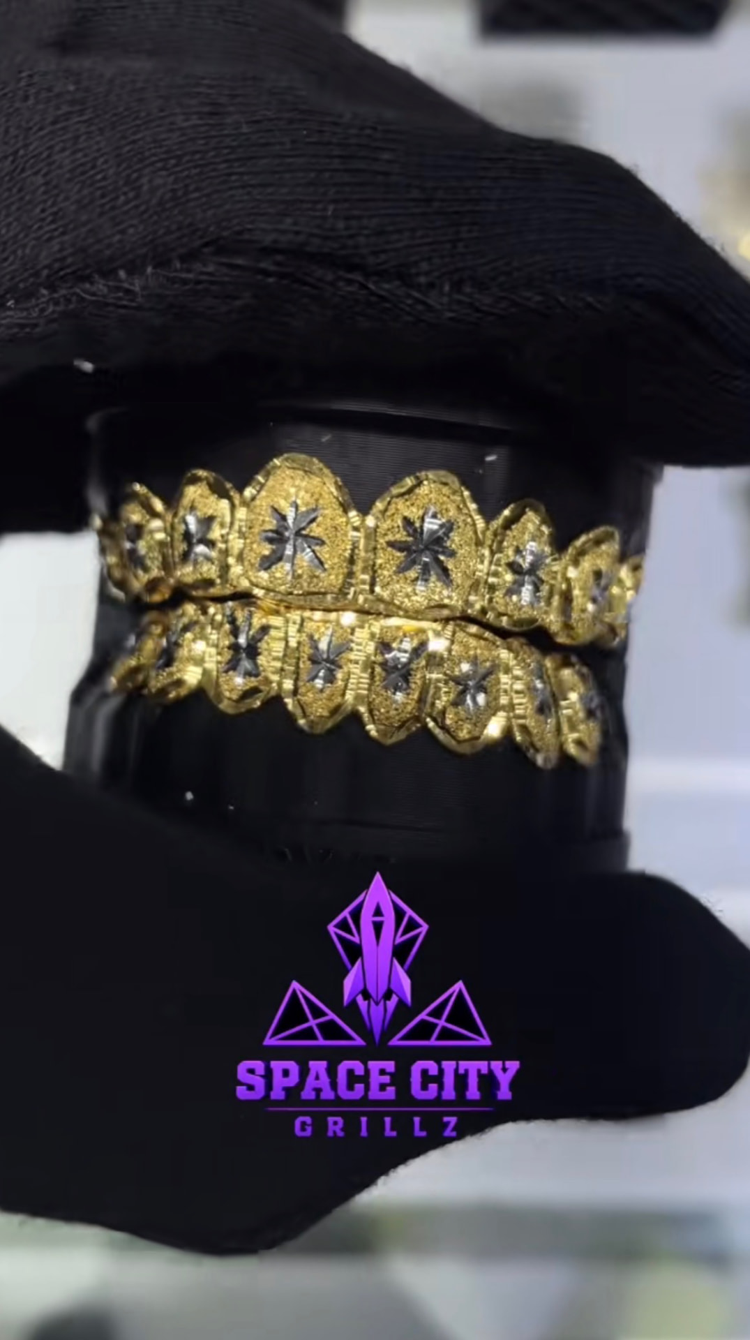 Gold two-row grill set with dark star-shaped detailing worn by a customer in a Space City Grillz cap
