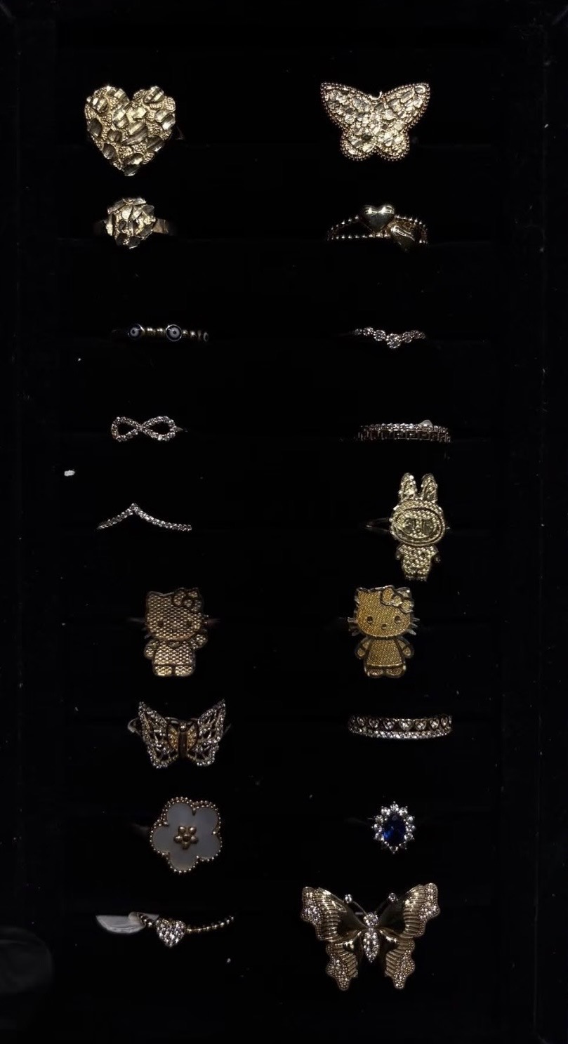 Assorted gold rings — hearts, butterflies, evil eyes and stone-set bands — arranged on black velvet